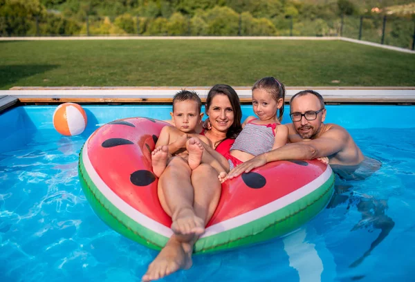 Familia joven con dos niños pequeños en la piscina al aire libre . —  Fotos de Stock