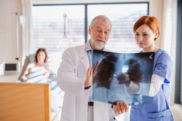 Ärzte stehen im Krankenhauszimmer und untersuchen ein Röntgenbild. — Stockfoto