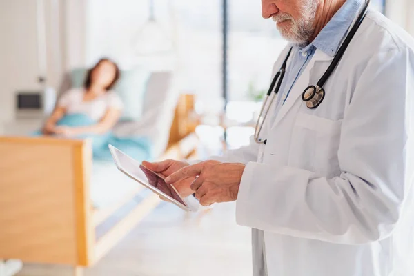 Unrecognizable doctor standing in hospital room, using tablet. — Stock Photo, Image