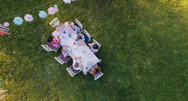 孩子们坐在露天花园宴会桌旁的空中照片. — 图库照片