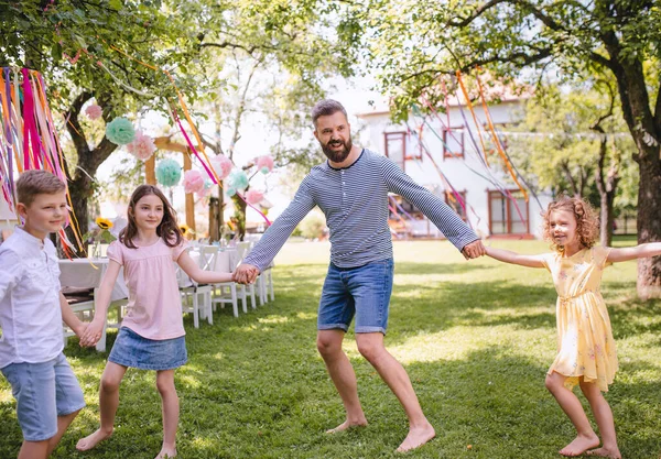 Férfi a gyerekek születésnapi party játszik szabadban a kertben nyáron. — Stock Fotó