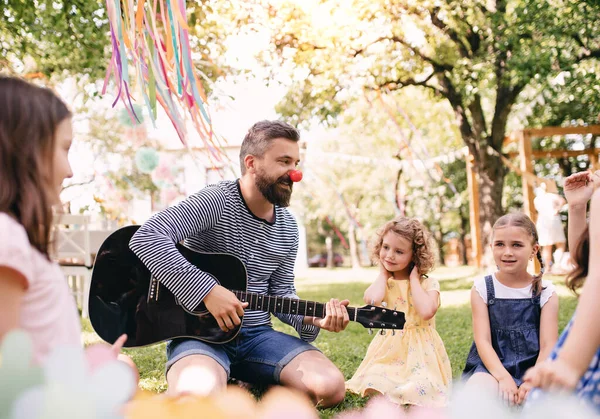 Küçük çocukları olan bir adam yazın bahçede gitar çalıyor.. — Stok fotoğraf