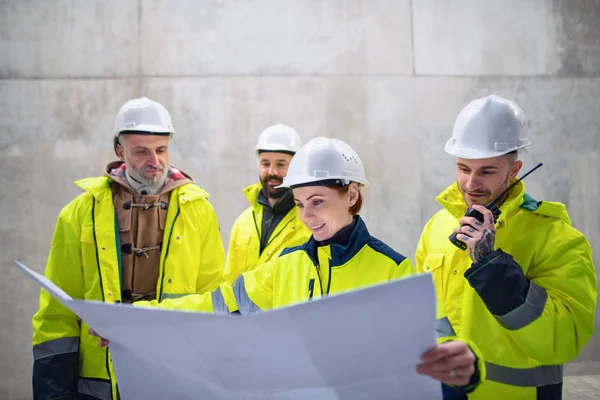 Un gruppo di ingegneri in piedi contro il muro di cemento in cantiere . — Foto Stock