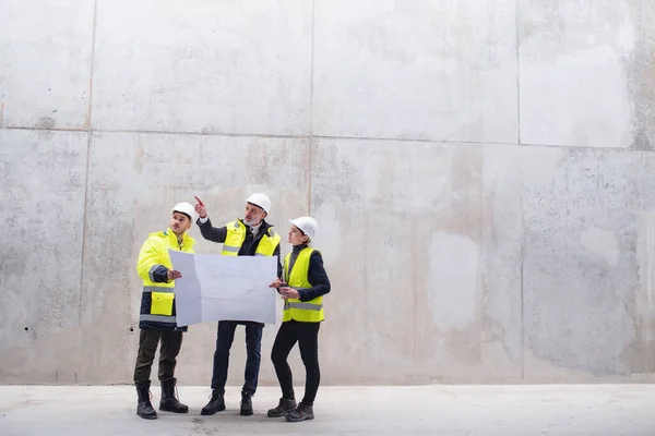 Un gruppo di ingegneri in piedi contro il muro di cemento in cantiere . — Foto Stock