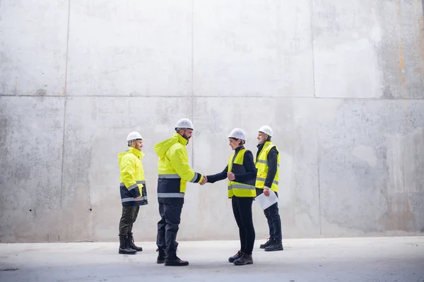 Un gruppo di ingegneri in piedi sul cantiere, stringendo la mano . — Foto Stock
