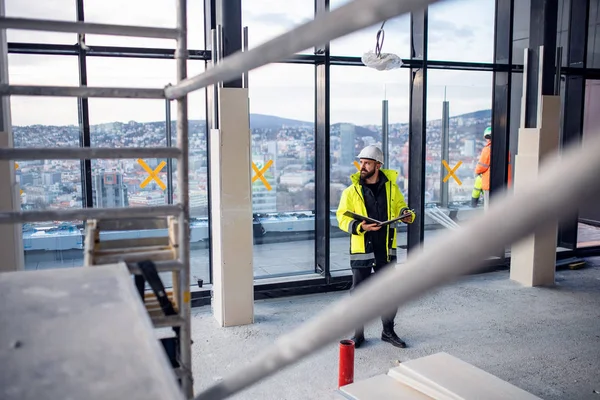 Man engineer standing on construction site, holding blueprints. — 스톡 사진