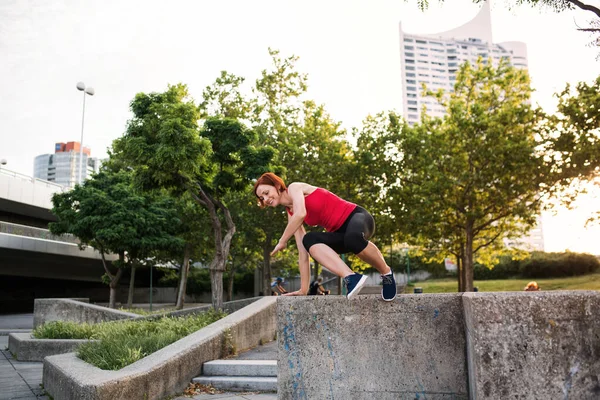 Junge Sportlerin springt in der Stadt von Betonmauer. — Stockfoto