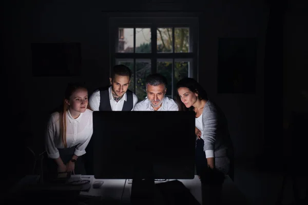 Група бізнесменів з комп'ютером в приміщенні в офісі, працює пізно . — стокове фото