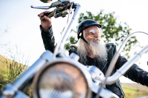 Uomo anziano viaggiatore con moto e occhiali da sole in campagna . — Foto Stock