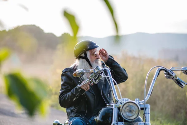 Старший путешественник с мотоциклом и солнцезащитными очками в сельской местности . — стоковое фото