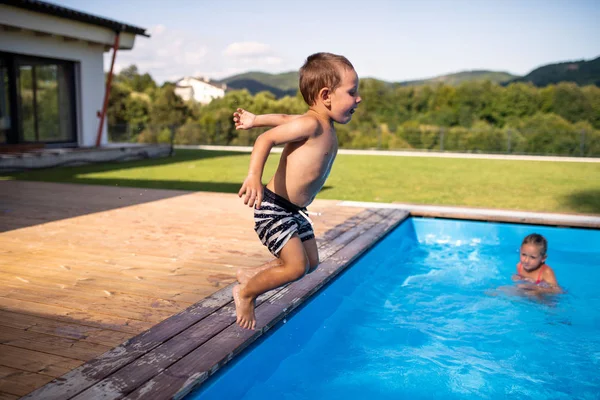 Dos niños pequeños jugando en la piscina al aire libre . —  Fotos de Stock