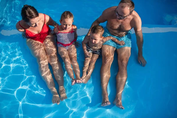 Yüzme havuzunda iki küçük çocuğu olan genç bir aile.. — Stok fotoğraf