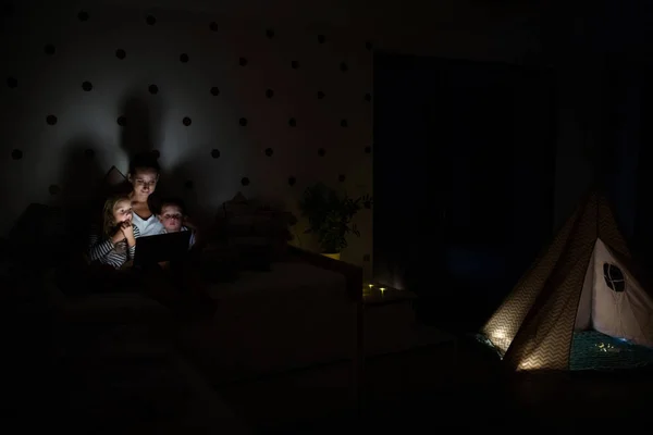 Giovane madre con bambini seduti in camera da letto, utilizzando il computer portatile . — Foto Stock