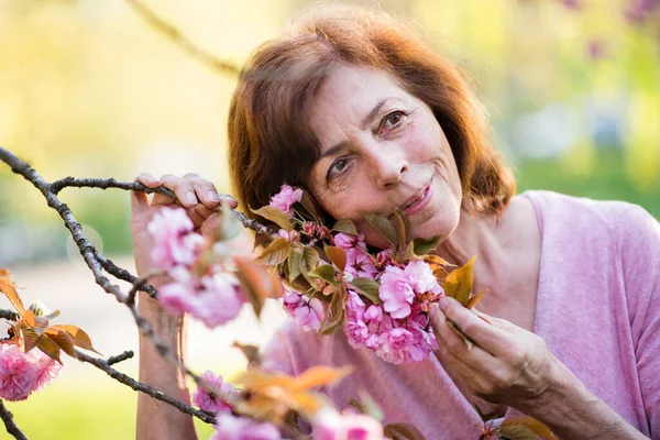 Beautiful senior woman standing outside in spring nature. Copy space. — Stock Photo, Image