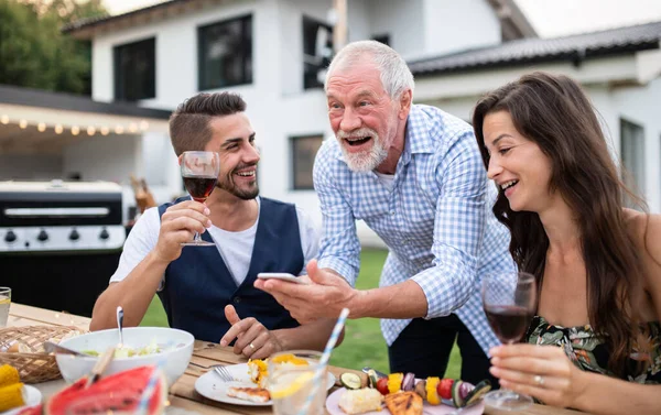 Porträt von Menschen im Freien beim Grillen im Garten der Familie mit dem Smartphone. — Stockfoto