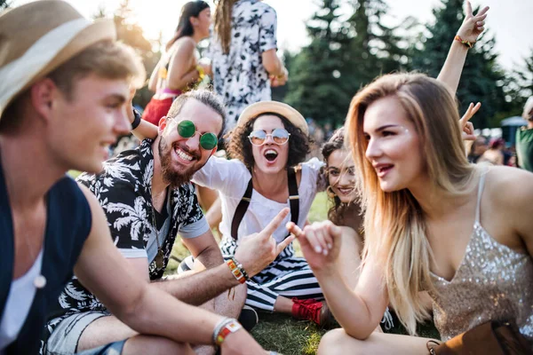 Grupo de jóvenes amigos sentados en el suelo en el festival de verano . — Foto de Stock