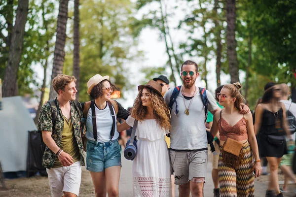 Widok z przodu grupy młodych przyjaciół z plecakiem spacerujących na letnim festiwalu. — Zdjęcie stockowe