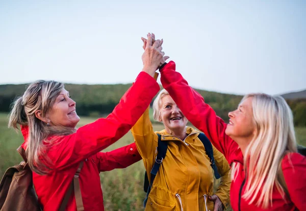 Senior women on walk outdoors in nature at dusk, giving high five. — Stock Photo, Image