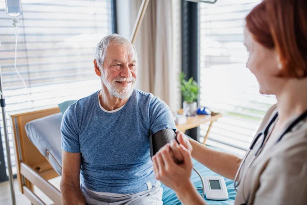 Ženský lékař vyšetřující seniorku v posteli v nemocnici. — Stock fotografie