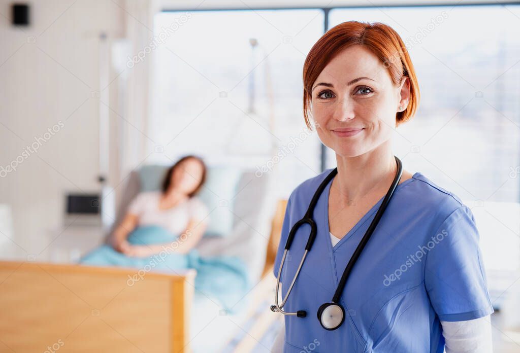 A doctor or nurse standing in hospital room, looking at camera.