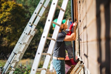 Bir baba ve küçük bir çocuk yazın dışarıda, ahşap ev boyuyor..