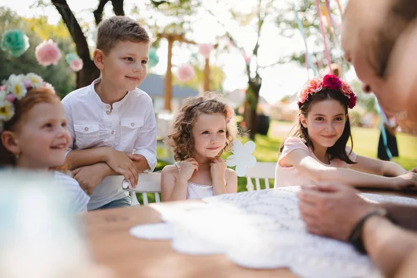 Niños pequeños sentados a la mesa al aire libre en la fiesta del jardín en verano . —  Fotos de Stock