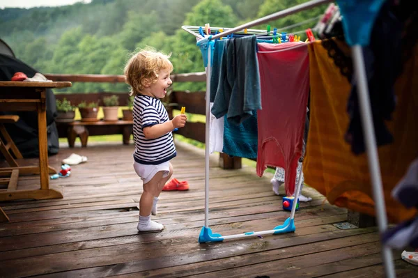 Тоддлер детей на открытом воздухе в летнее время, играя с одеждой сушки вешалку . — стоковое фото