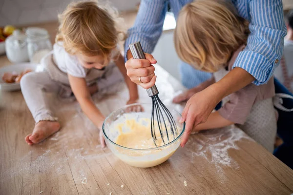 Акушерское отделение матери с двумя маленькими детьми на кухне, приготовление пищи . — стоковое фото
