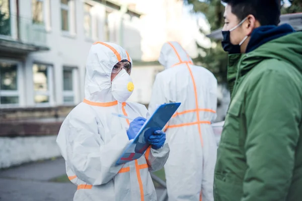 Personas con trajes de protección ayudando al hombre al aire libre, concepto coronavirus . —  Fotos de Stock