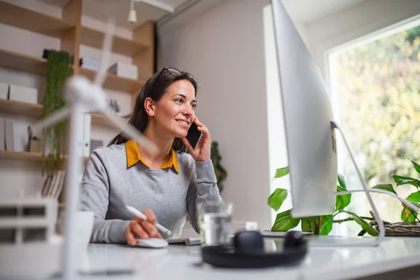 Attraktive Geschäftsfrau, die drinnen im Büro am Schreibtisch sitzt und das Smartphone benutzt. — Stockfoto