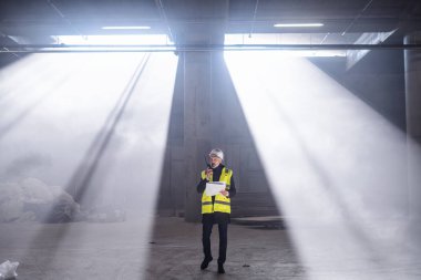 Man engineer using walkie talkie on construction site.