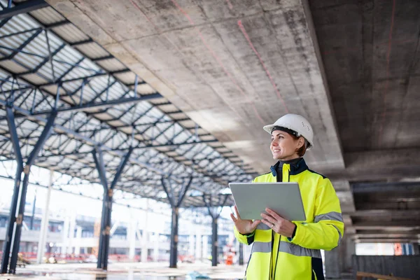 Een vrouw ingenieur met tablet staan op de bouwplaats, werken. — Stockfoto