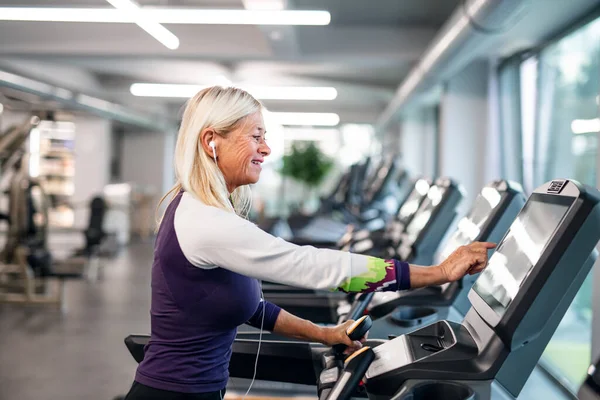 Una mujer mayor en el gimnasio haciendo ejercicio cardiovascular . — Foto de Stock