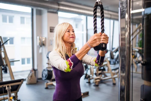 Um retrato da mulher idosa no ginásio, fazendo exercício . — Fotografia de Stock