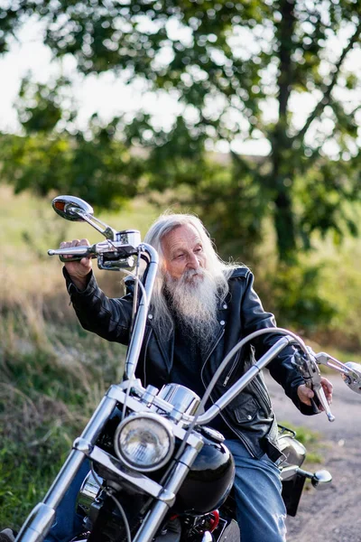 Ein älterer Mann, der mit seinem Motorrad auf dem Land unterwegs ist. — Stockfoto