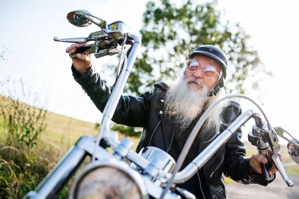 Starší muž cestovatel na motorce a slunečních brýlích na venkově. — Stock fotografie