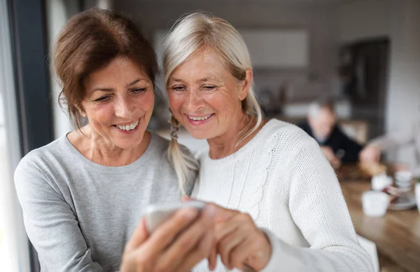 Groep van senior vrienden thuis, met smartphone. — Stockfoto