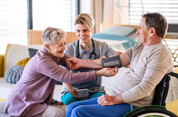 Zdravotnický pracovník navštěvující seniorského pacienta na vozíčku doma. — Stock fotografie