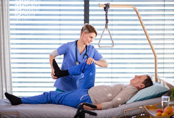 A healthcare worker and senior patient in hospital, physiotherapy. — Stock Photo, Image