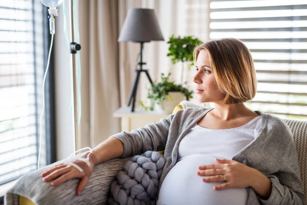 Portret kobiety w ciąży z kroplówką dożylną w domu lub w szpitalu. — Zdjęcie stockowe