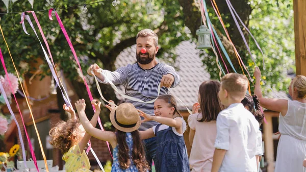 Mann mit Kindern auf Geburtstagsparty spielt im Sommer im Garten. — Stockfoto