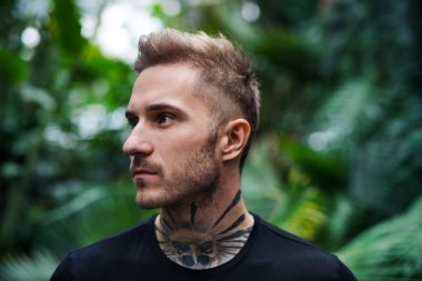 Botanik bahçesinde dikilen genç adamın ön görüntüsü.