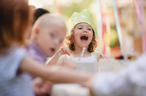 Niños pequeños sentados a la mesa al aire libre en la fiesta del jardín en verano . — Foto de Stock