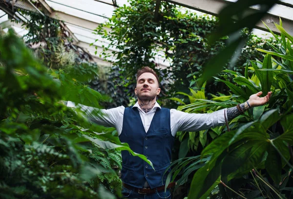 Botanik bahçesinde kollarını açmış duran genç adam.. — Stok fotoğraf