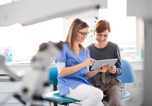 Un dentista hablando con una mujer en cirugía dental, un chequeo dental . —  Fotos de Stock