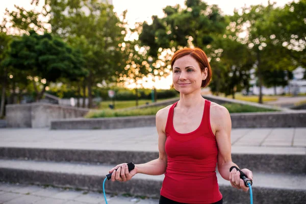 Młoda kobieta robi ćwiczenia na świeżym powietrzu w mieście ze skakanką. — Zdjęcie stockowe