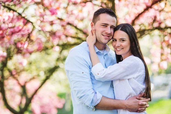 Young couple in love standing outside in spring nature. — Stock Photo, Image
