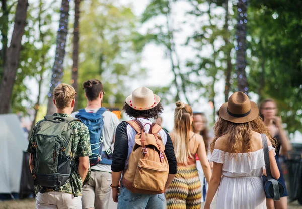 Rear view of group of young friends with backpack walking at summer festival. — Stock Photo, Image