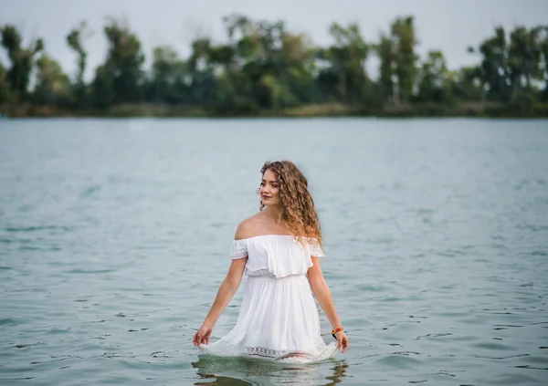 Pohled na mladou ženu na letním festivalu, stojící v jezeře. — Stock fotografie