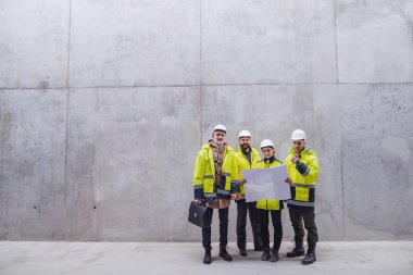 İnşaat alanında beton duvara karşı duran bir grup mühendis..
